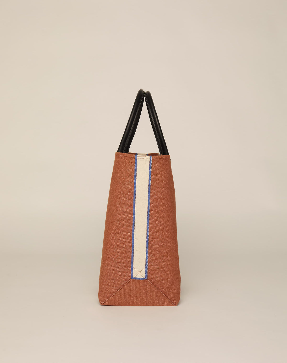 Image of side of medium-sized classic canvas tote bag in tan colour with black leather handles and contrasting stripes.