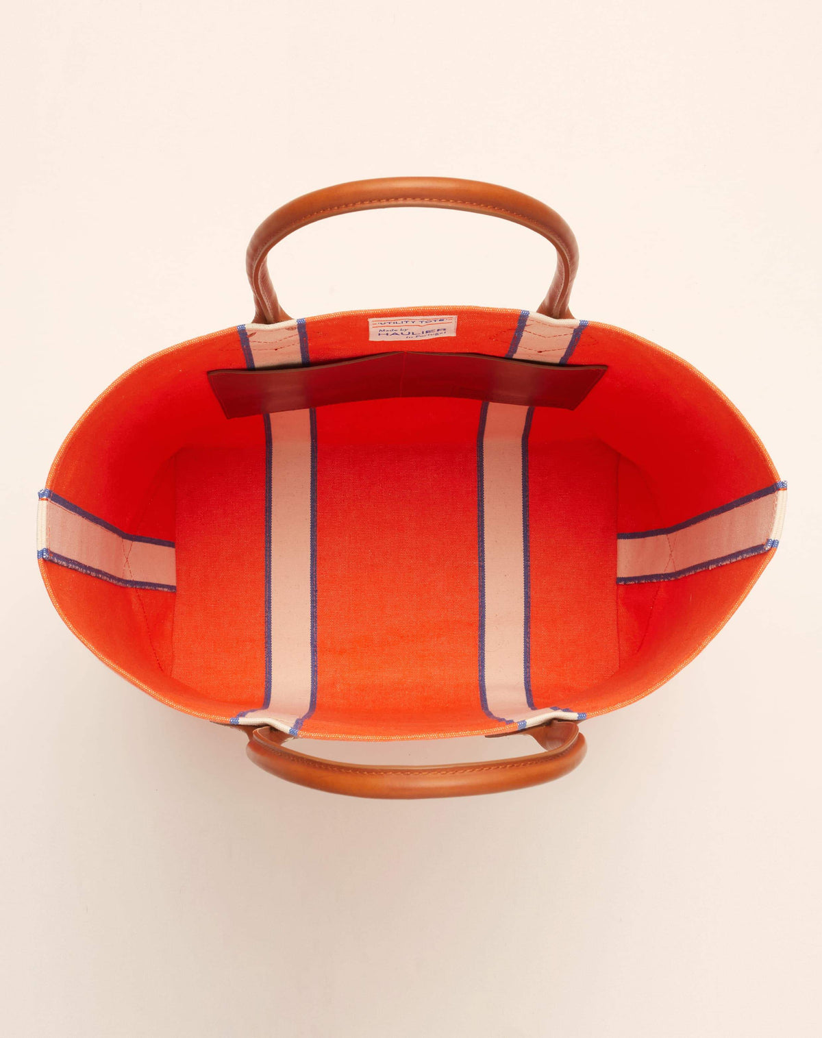 Image of inside of medium-sized classic canvas tote bag in orange colour with tan leather handles and contrasting stripes.