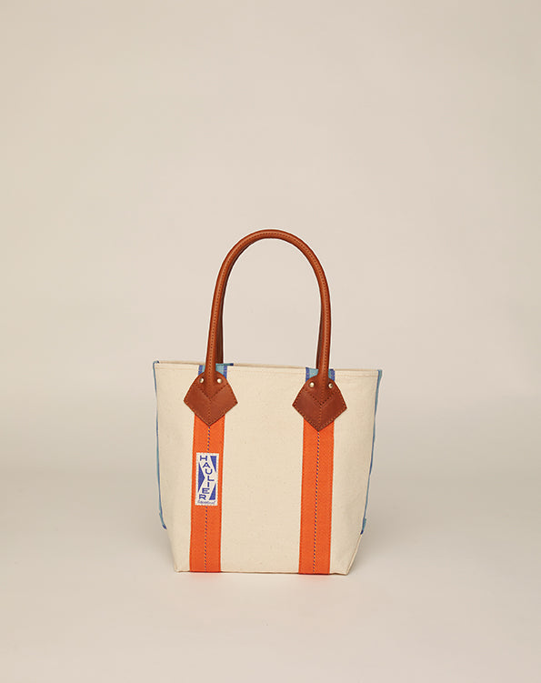 Side image of small classic canvas tote bag in tan colour with black leather handles and contrasting stripes.