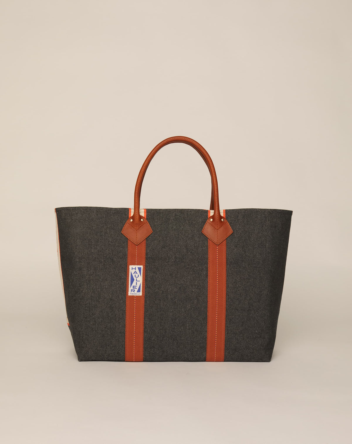 Image of classic canvas tote bag in washed black colour with tan leather handles and contrasting stripes.