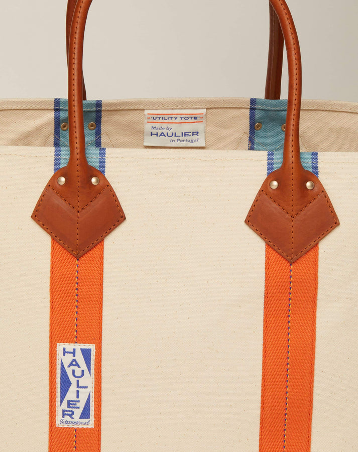 Close-up image of medium-sized classic canvas tote bag in natural ecru colour with tan leather handles and contrasting stripes and HAULIER branding.