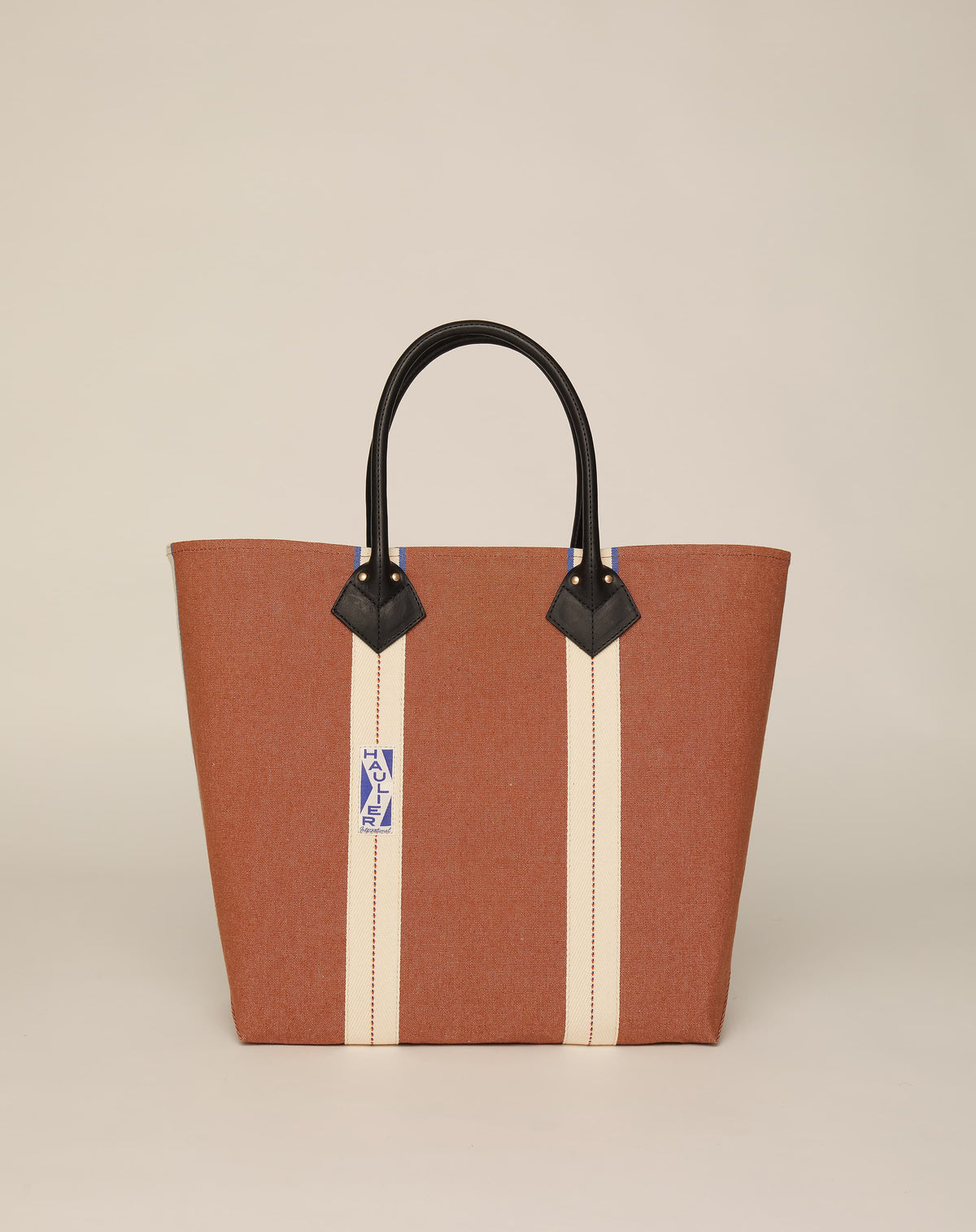 Image of medium-sized classic canvas tote bag in tan colour with black leather handles and contrasting stripes.