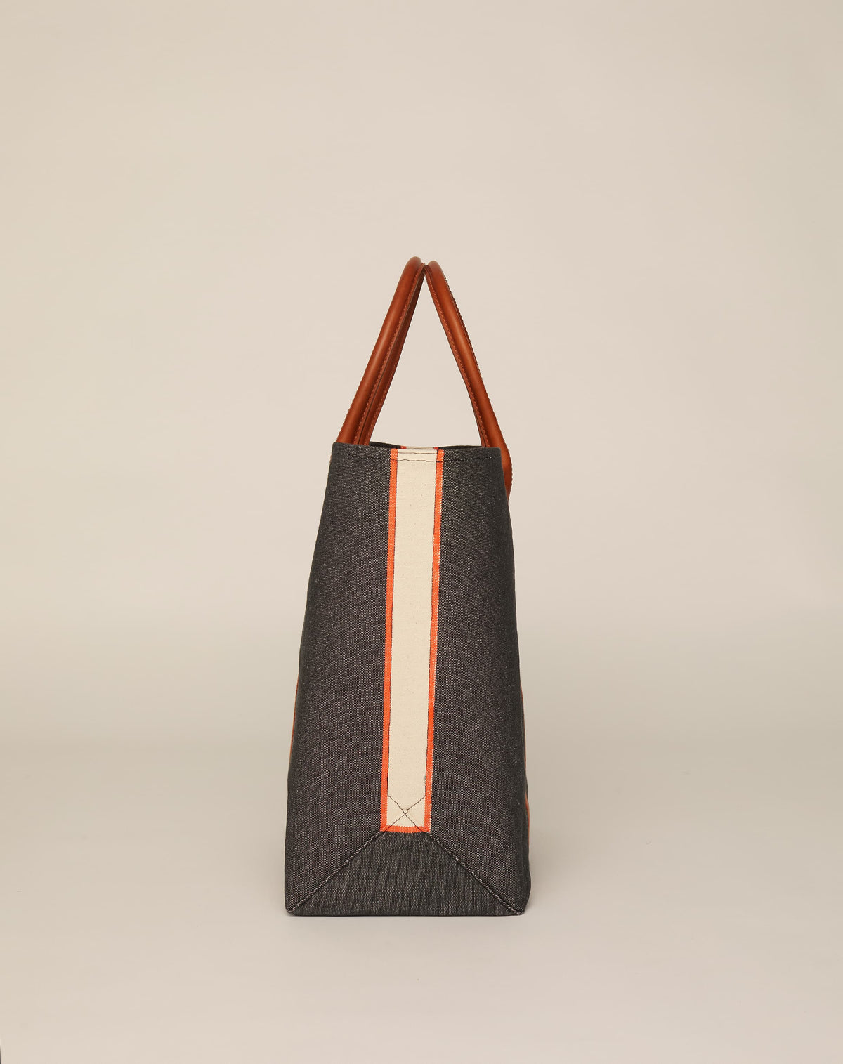 Side image of medium-sized classic canvas tote bag in washed black colour with tan leather handles and contrasting stripes.