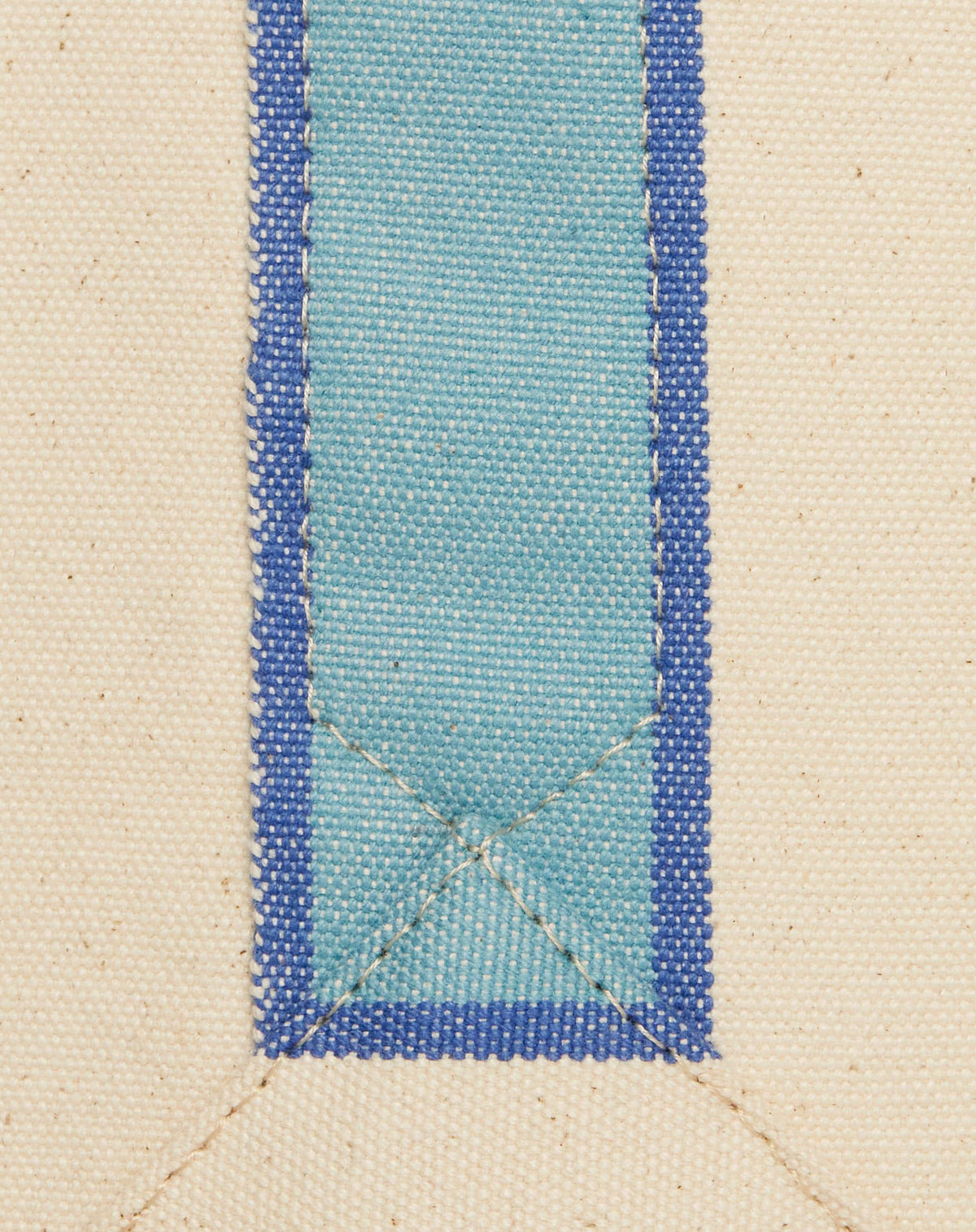 Close-up image of light blue stripe on canvas bag with stitch detail.