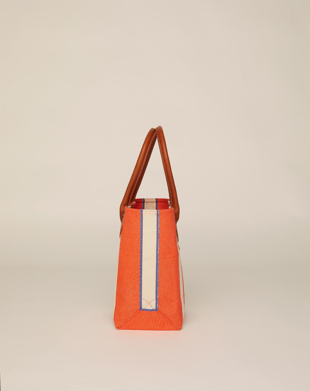 Side image of small classic canvas tote bag in orange colour with tan leather handles and contrasting stripes.