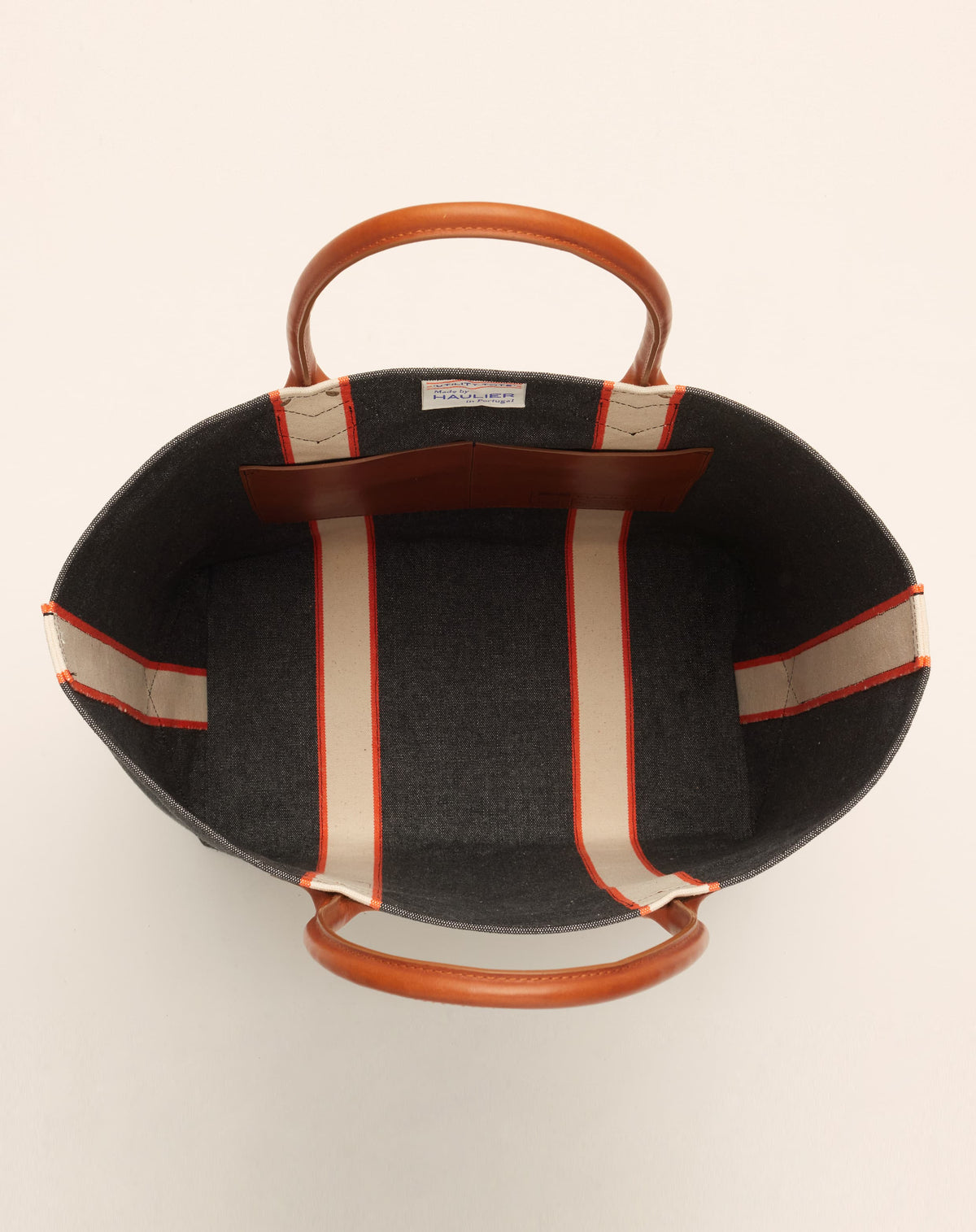 Image of inside of medium-sized classic canvas tote bag in washed black colour with tan leather handles and contrasting stripes.
